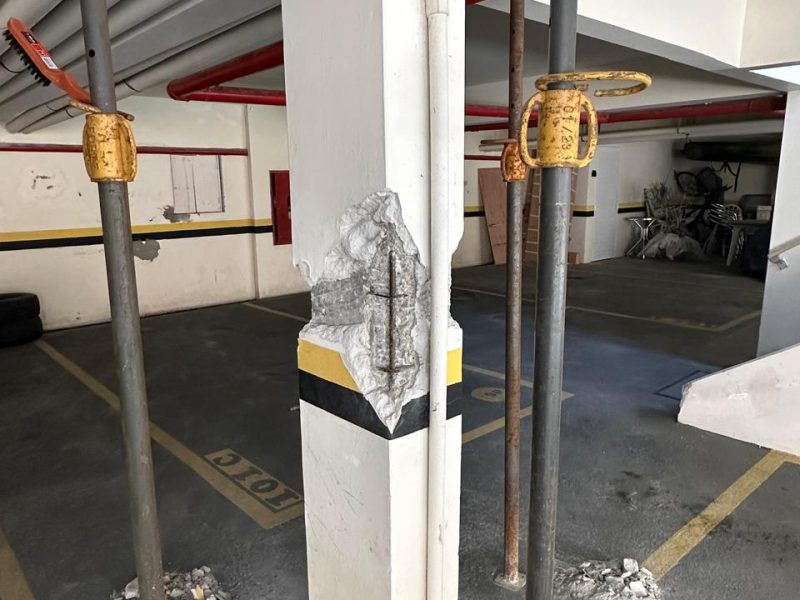Nicho aberto em pilar de garagem com armadura exposta e escoramento montado