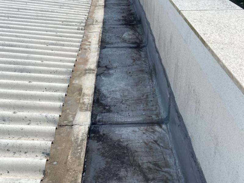 Calha de concreto entre a telha e a platibanda com sedimento escuro acumulado