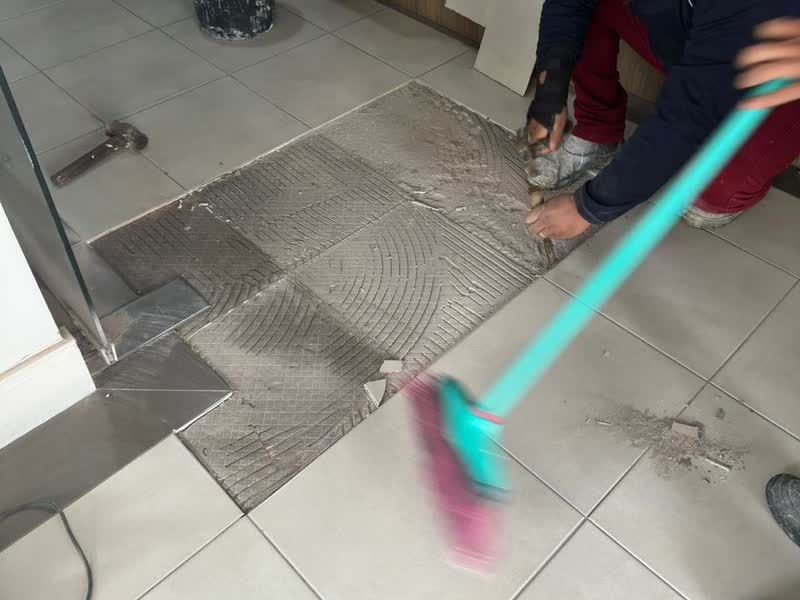 Assentamento de piso novo sobre argamassa penteada em área comum de edifício